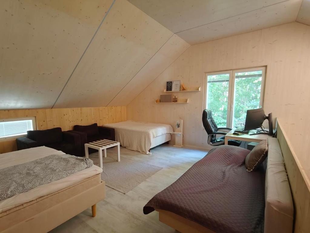 a attic room with a bed and a desk with a laptop at The other side of the CLT semi-detached house, with a separate SPA in Lahti