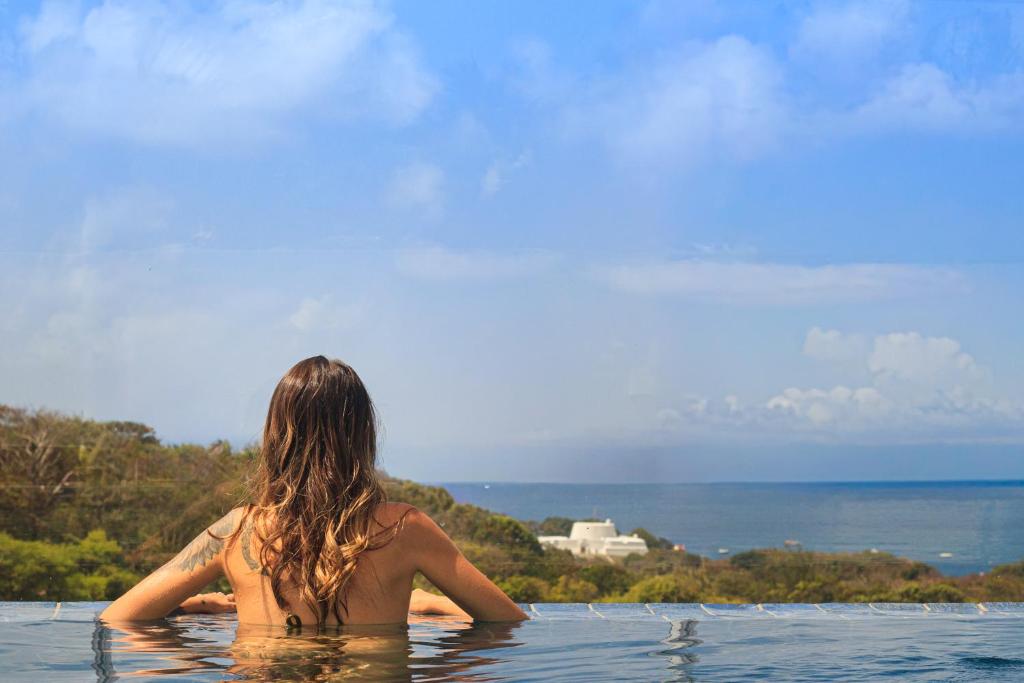 Eine Frau sitzt im Wasser in einem Infinity-Pool. in der Unterkunft Pousada Village Premiere in Fernando de Noronha