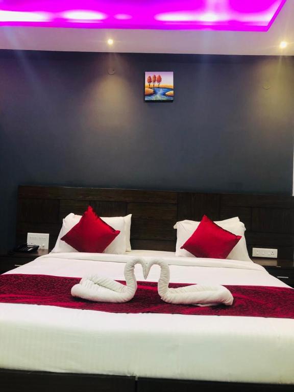 a bedroom with a large bed with red pillows at Coorg ASHOK PALACE in Madikeri