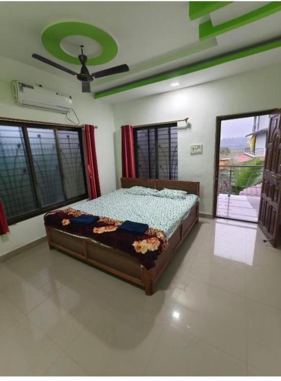 a bedroom with a bed in a room with windows at Divyesh Holiday Home in Nagaon