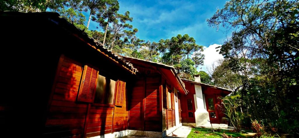 a red brick house with trees in the background at Wooden House in Maria da Fé
