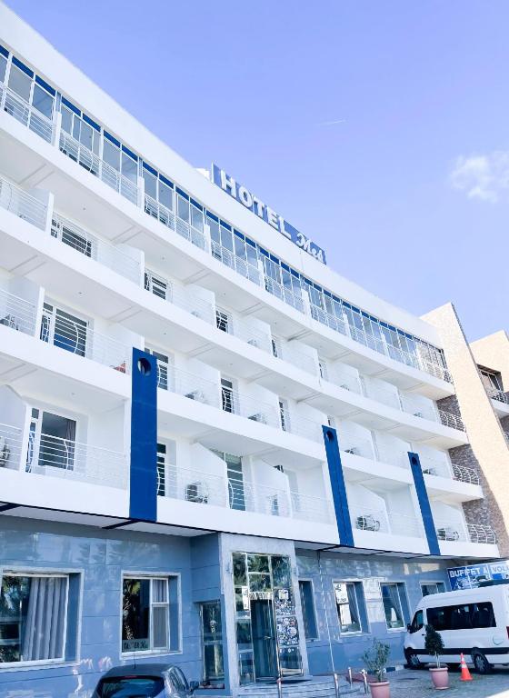 a large white building with cars parked in front of it at Tanger Med Hotel, Conference & Catering in Ghdar Defla