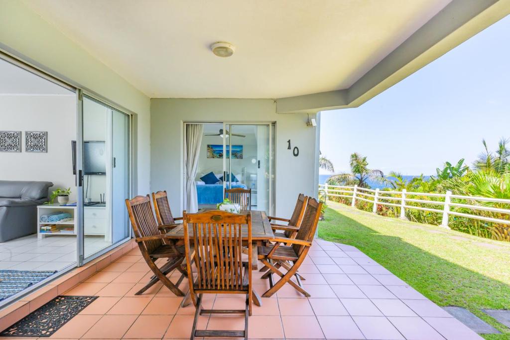 a dining room with a table and chairs on a patio at Sea-Renity 10 in Umdloti