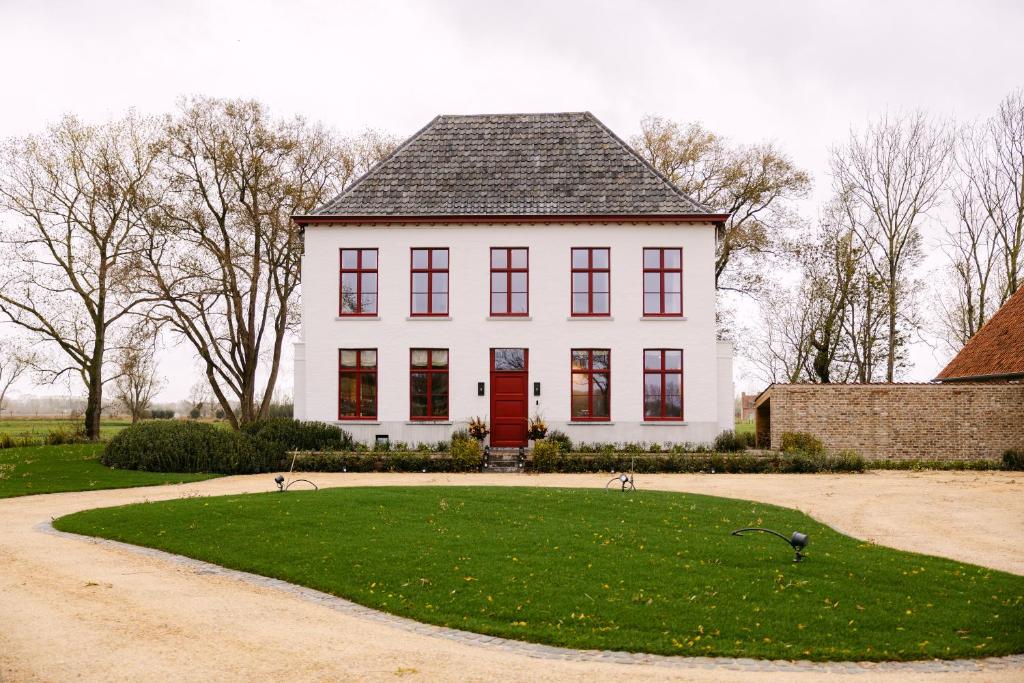 达默De Snippe的一栋白色的大房子，门是红色的，坐落在绿色的草坪上。