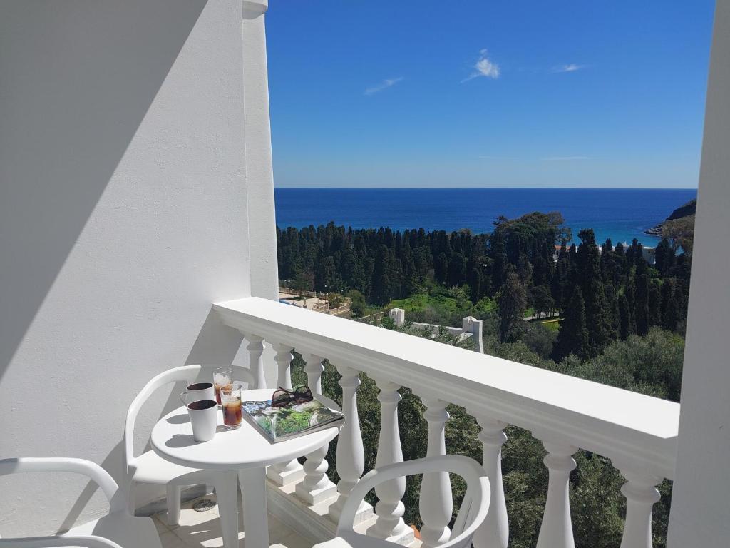 un balcone bianco con tavolo, sedie e vista sull'oceano di Dimitra's Pretty Apartment 4 klm away from Chora ad Andro