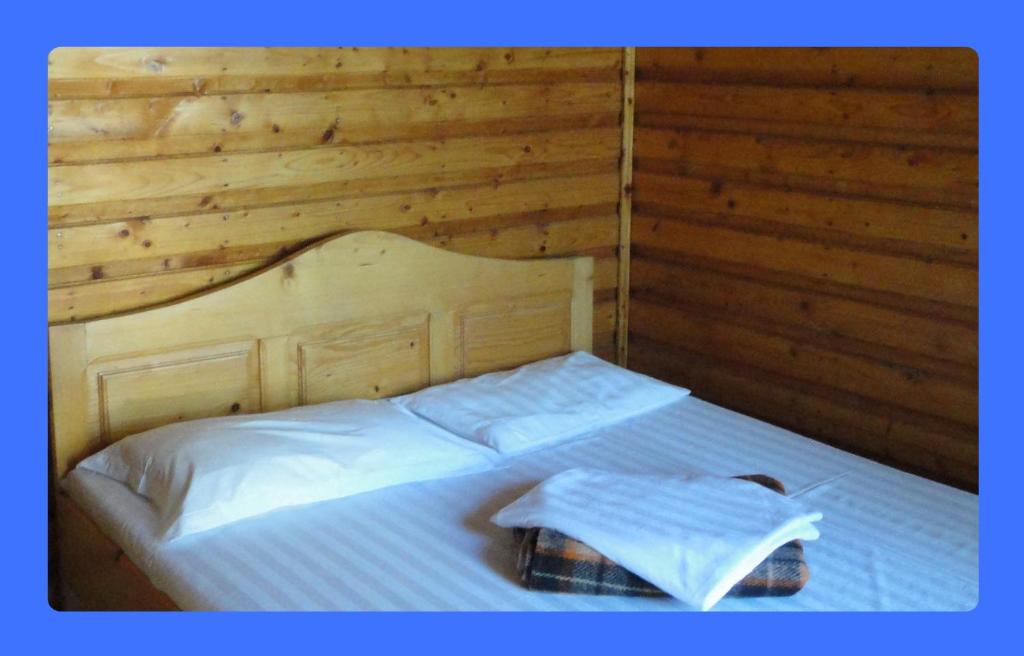 1 dormitorio con 1 cama blanca y paredes de madera en Satul de Vacanta Campo Euro Club, en Partizanii