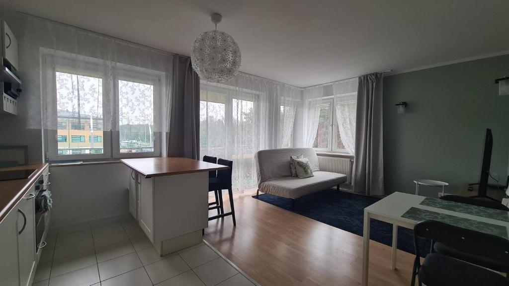 a kitchen and living room with a table and a chair at Apartament Leśny Ząbki in Ząbki