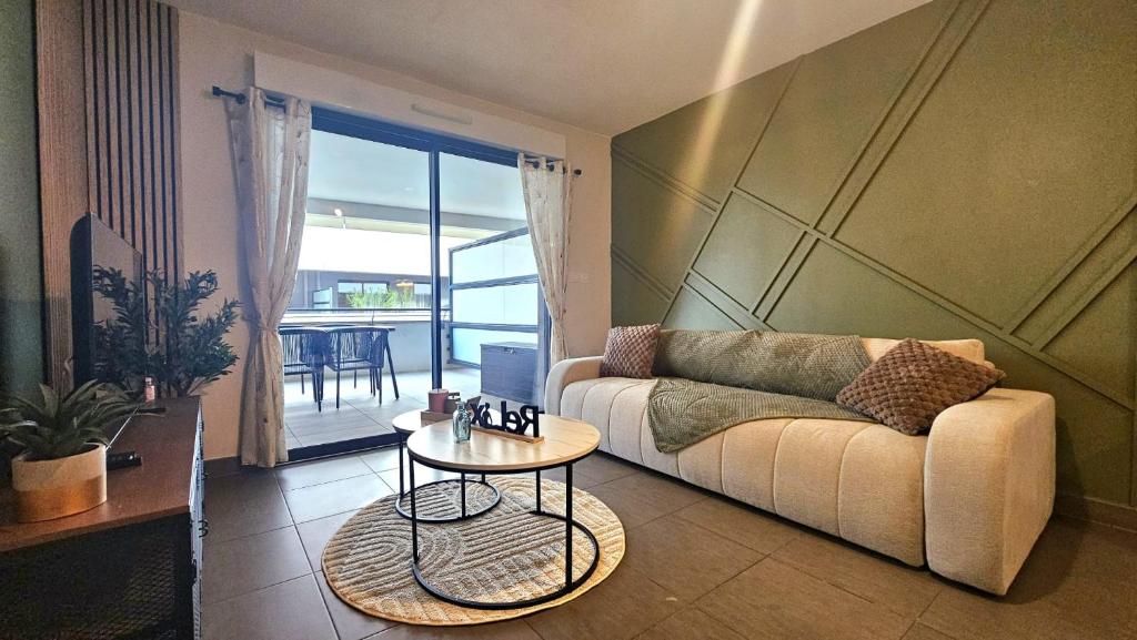 een woonkamer met een bank en een tafel bij Appartement Standing 5mn Village de Noël in Le Barcarès