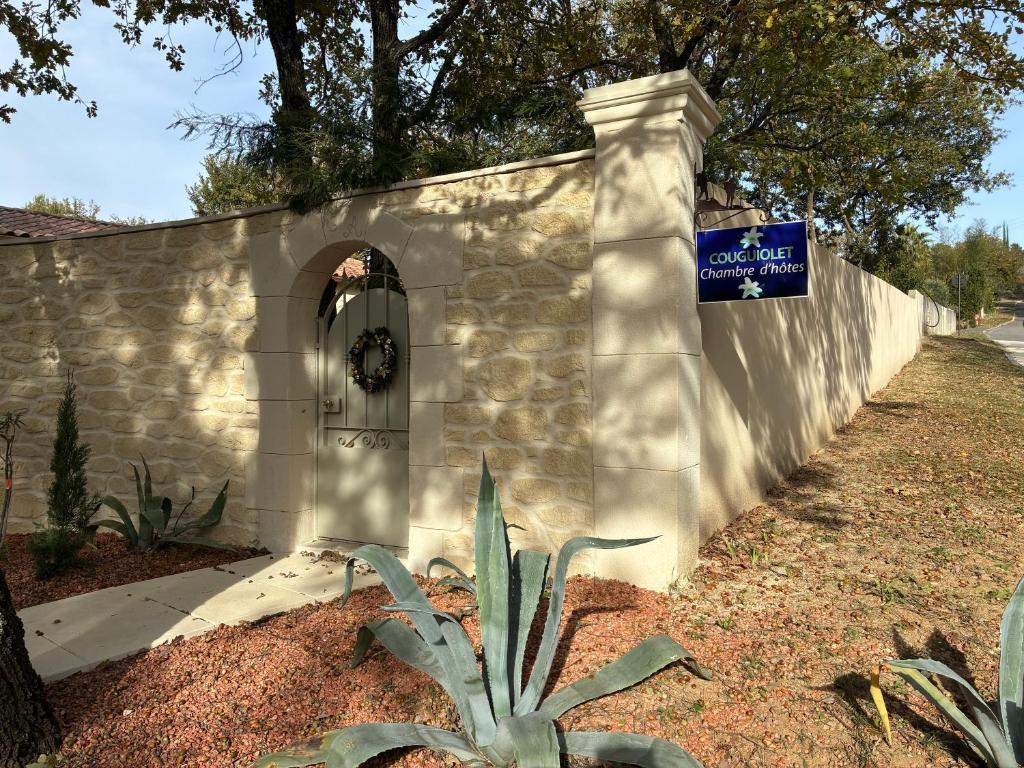 a stone wall with a door and a sign on it at Chambre d'Hôte Couguiolet - avec piscine in Foissac