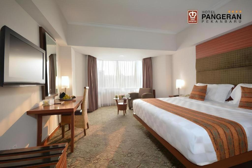 北干巴鲁parma panam pekanbaru的配有一张大床和一张书桌的酒店房间