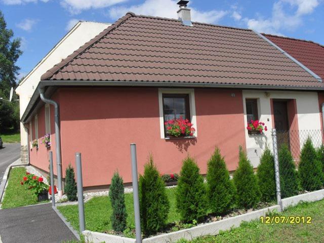 a small house with flowers in the window at Domeček u Terčina Údolí in Nové Hrady