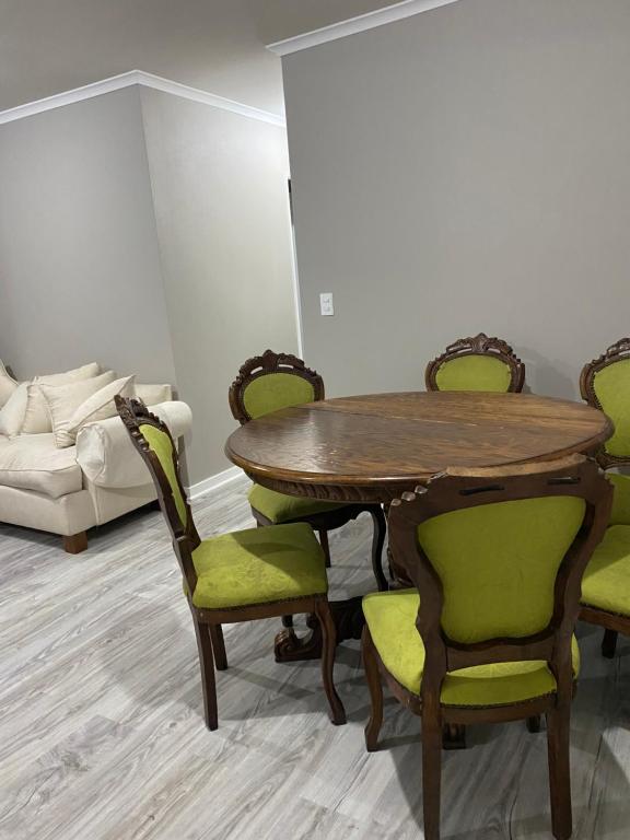 una sala da pranzo con tavolo in legno e sedie verdi di Hospedaje curauma a Lago Peñuelas