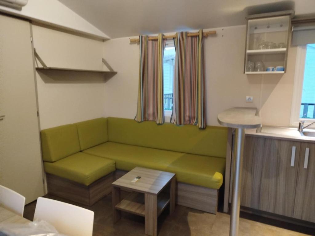 un soggiorno con un divano verde e un tavolo di Mobil-home 6 places dans camping 4 étoiles a Lit-et-Mixe