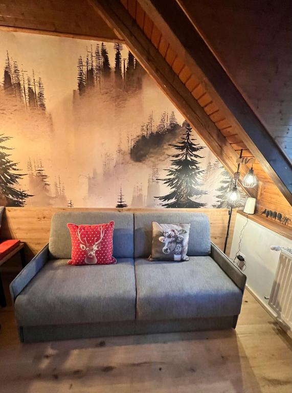 a couch with pillows on it in front of a wall at Melodia del bosco in Tarvisio