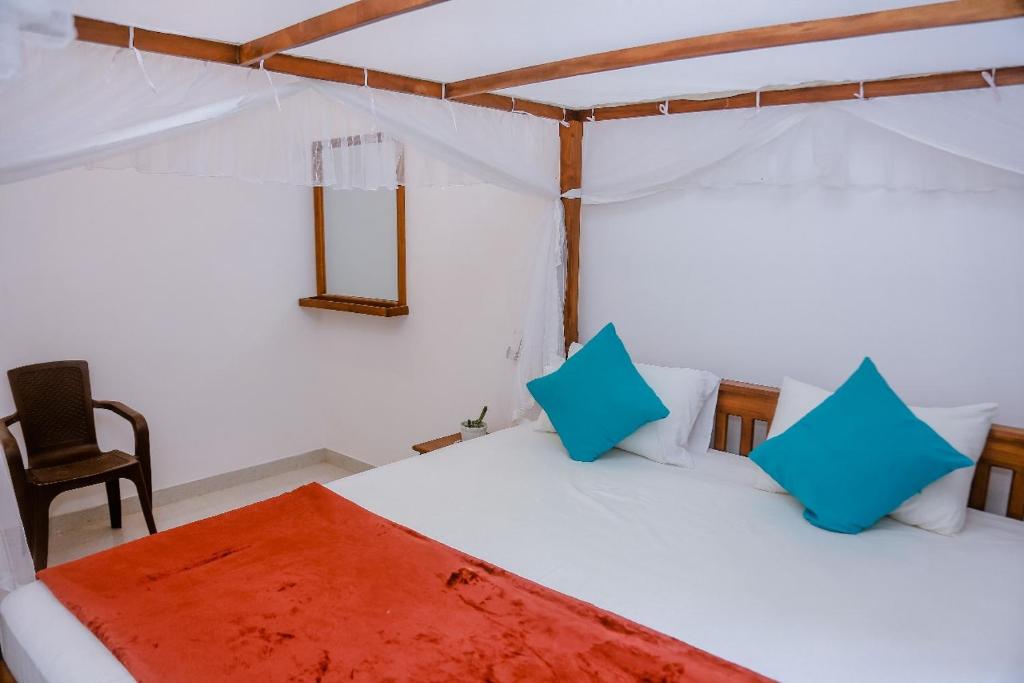 a bedroom with a bed with blue pillows and a chair at Femingo by Costels in Hiriketiya