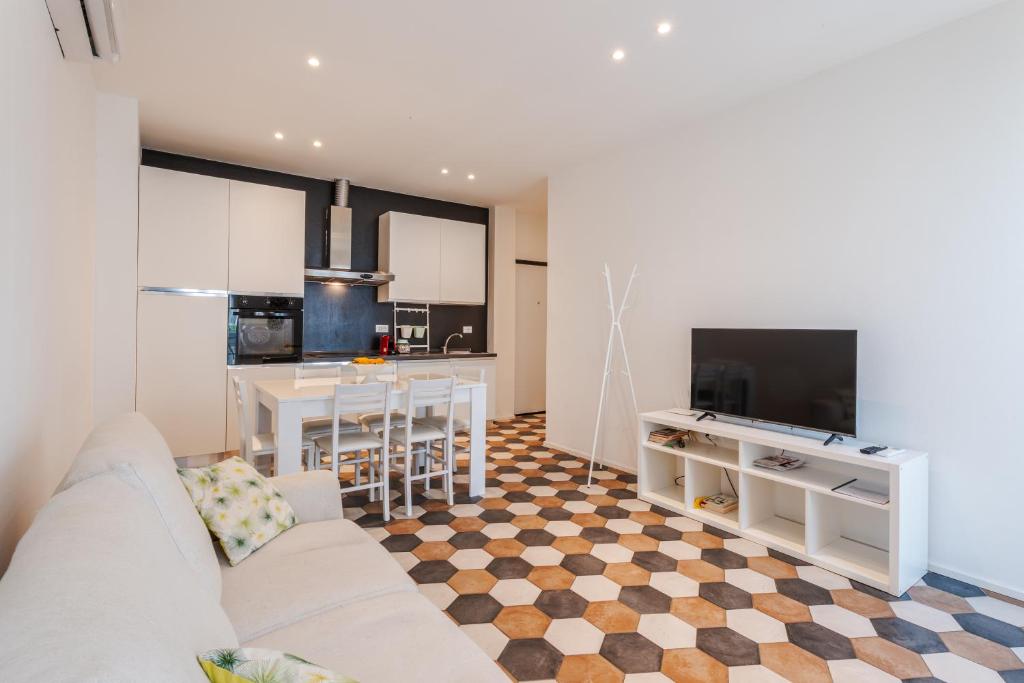 a living room with a white couch and a kitchen at Ippolito - Free WiFi & Air Conditioning in Faenza