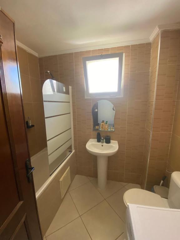 Un baño con lavabo, inodoro y ventana. en Spacious Apartment F5 Tangier, en Gzennaïa