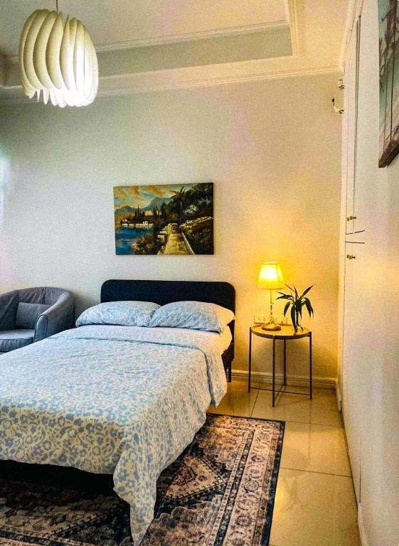a bedroom with a bed and a table with a lamp at Apolonia Transient House- The White Room in Baguio