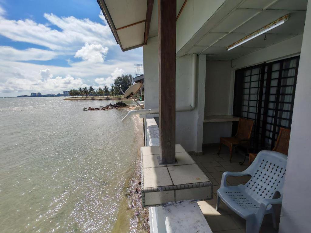 a house with two chairs and the water at seaview beach homestay pd ground floor in Port Dickson