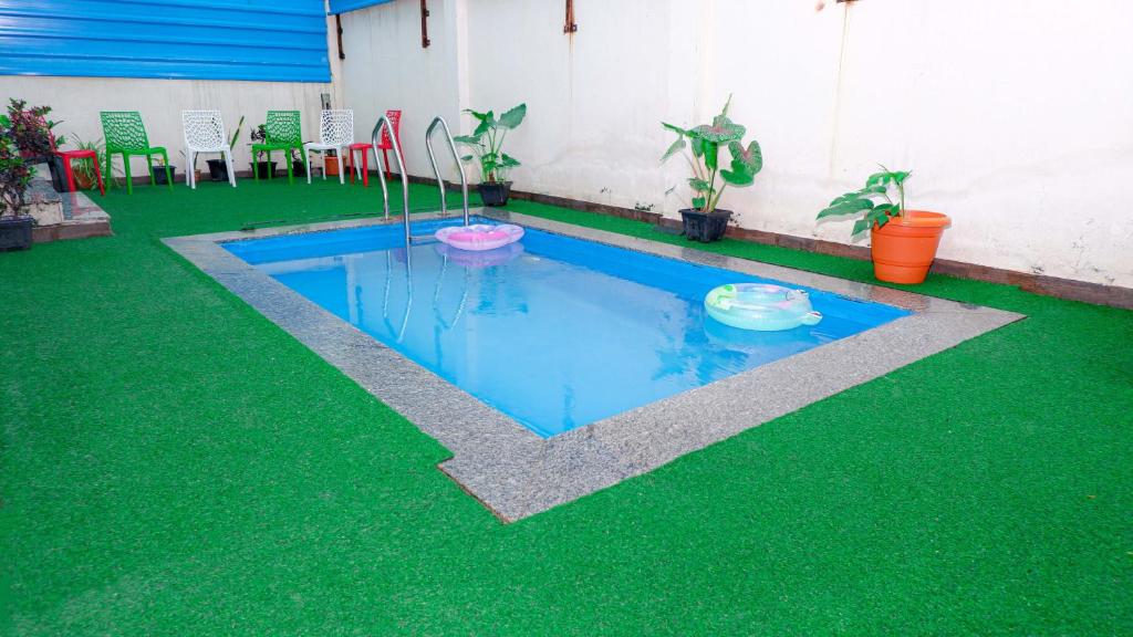 Una pequeña piscina con suelo verde y algunas plantas. en The Sea Garden, en Mahabalipuram