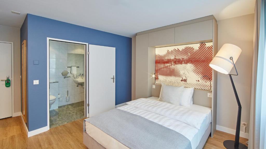 a bedroom with a large bed and a bathroom at Hotel Wettstein in Basel