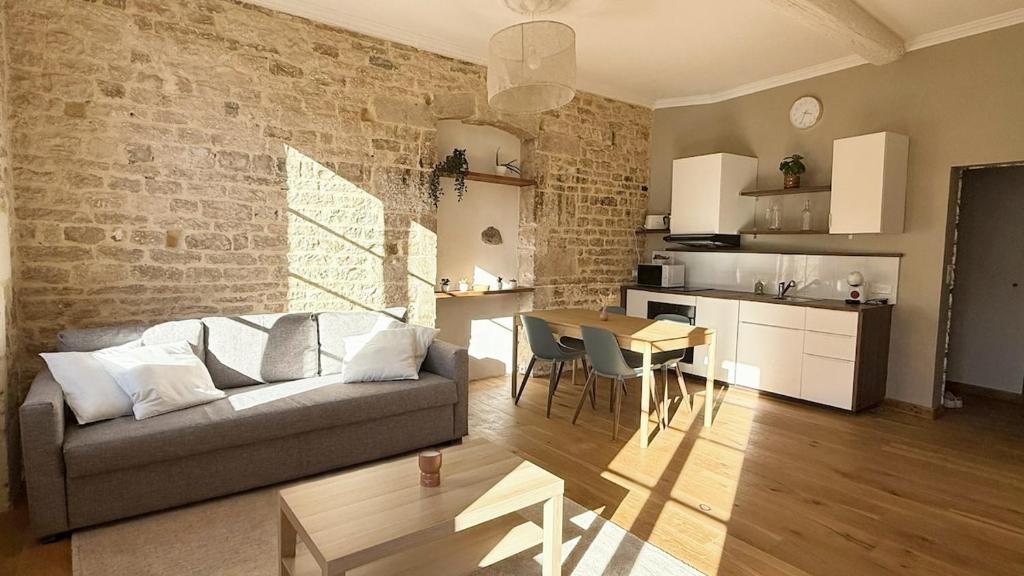 a living room with a couch and a table and a kitchen at La Calade Charming Apartment in Nîmes