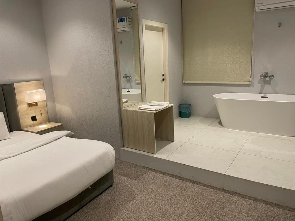 een badkamer met een bed, een bad en een wastafel bij Bunyan Alula Hotel in Al Ula