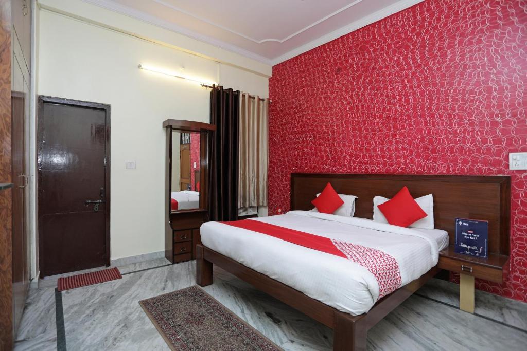Un dormitorio con una cama grande y una pared roja. en Hotel O Shikhar Paradise, en Gomti Nagar