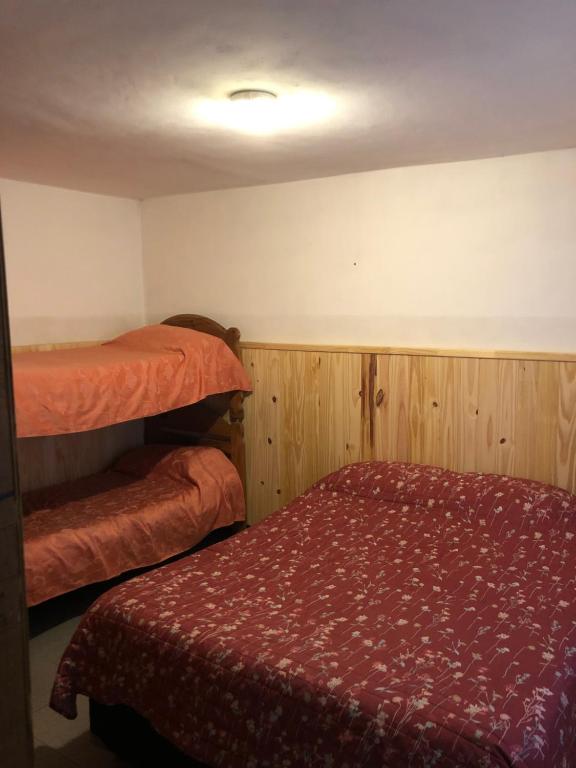 una camera con 2 letti a castello e un copriletto rosso di Piltri2 monoambiente a El Bolsón