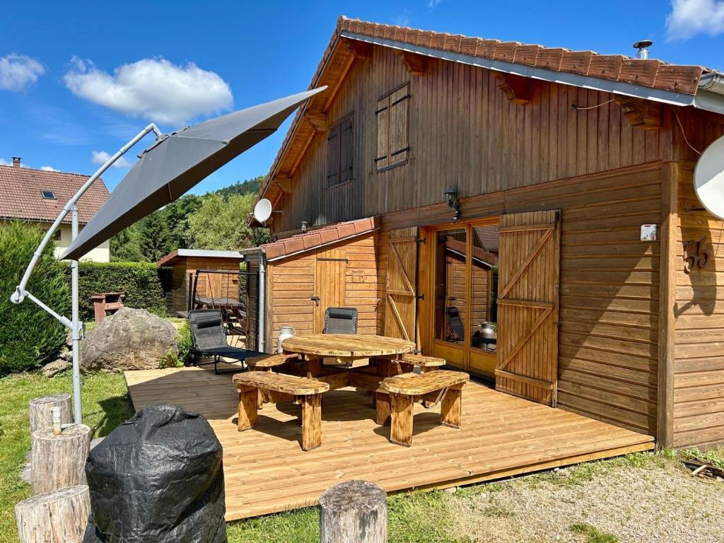 een houten terras met een picknicktafel en een parasol bij Chalet exposition plein sud in Xonrupt-Longemer