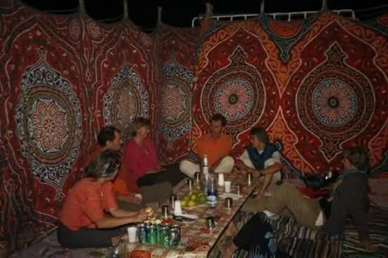 un grupo de personas sentadas alrededor de una mesa en una habitación en White Desert Safari trip , two days one night camping, en Bawati