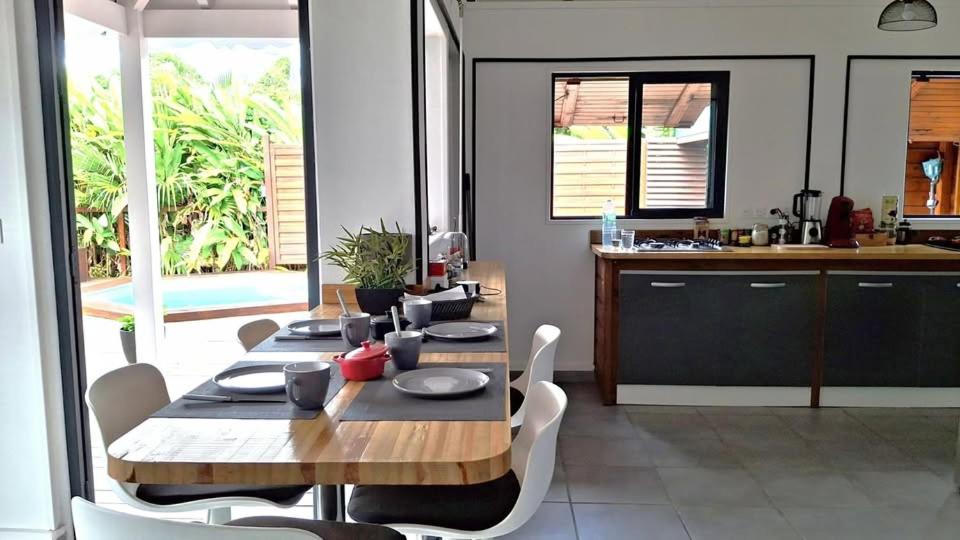 Location saisonnière في بيتي-بور: غرفة طعام مع طاولة وكراسي ومطبخ