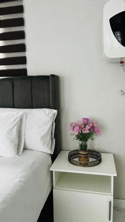 4 at Granada في شرق لندن: مزهرية من الزهور على موقف ليلي بجوار سرير