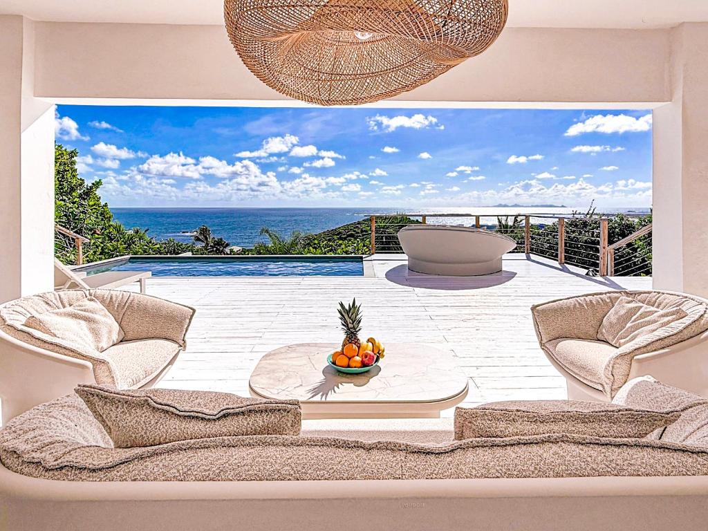 a living room with a couch and a bowl of fruit at Villa Atao, sublime view of Orient Bay and the islands in Cul de Sac