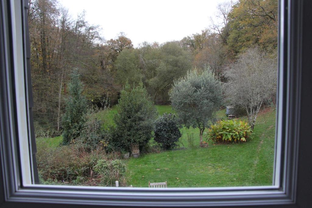 una finestra con vista su un giardino con alberi e cespugli di Chambre d'hôtes cosy à la campagne a Bourg-des-Comptes