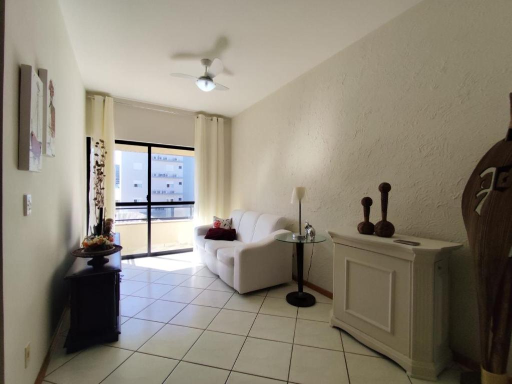 Una sala de estar con un sofá blanco y una ventana. en B362 - Cobertura a poucos passos do mar com piscina privativa., en Bombas