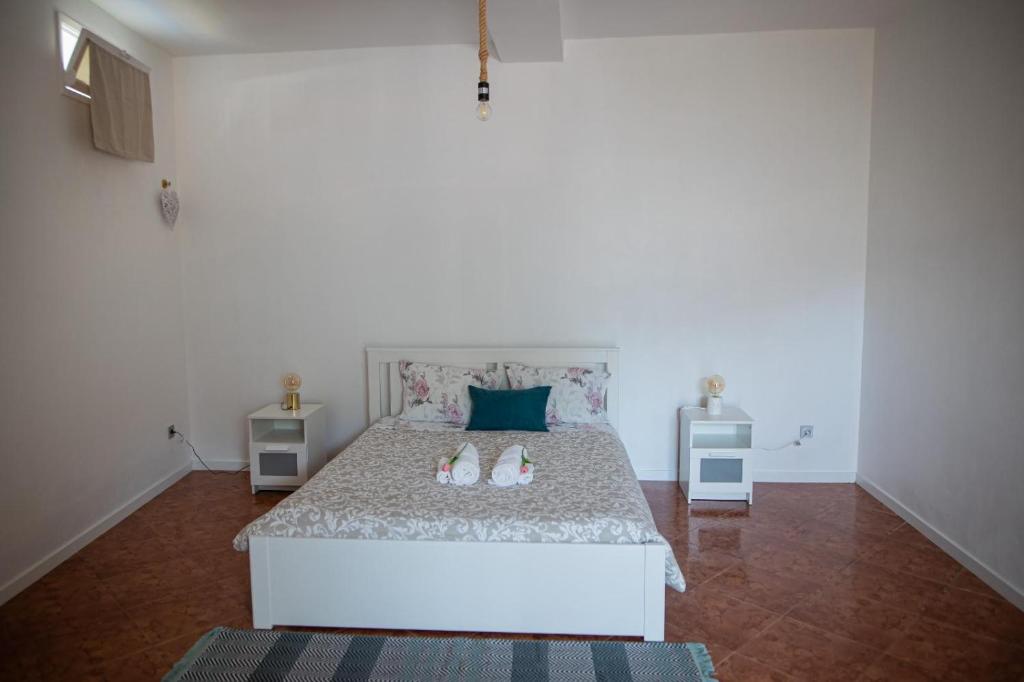 um quarto com uma cama branca com sapatos em spot do vale em Machico