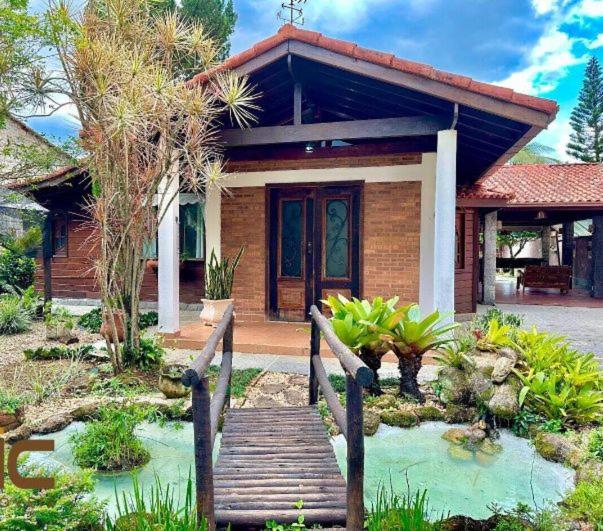 a small house with a wooden bridge in front of it at Alfa Serra lago e montanha in Guapimirim