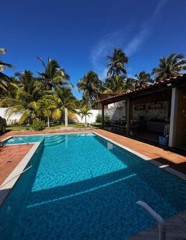 a swimming pool in front of a house with palm trees at Casa Maresia Ponta da Asa in Coruripe