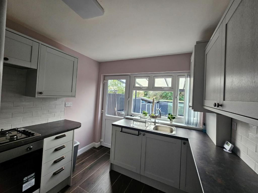 a kitchen with white cabinets and a sink and a window at Elim House in Birmingham