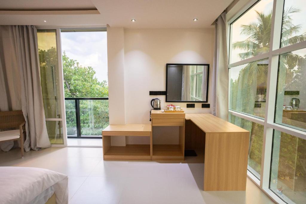 a bedroom with a desk with a television and windows at Aqua Luna Dhangethi in Dhangethi