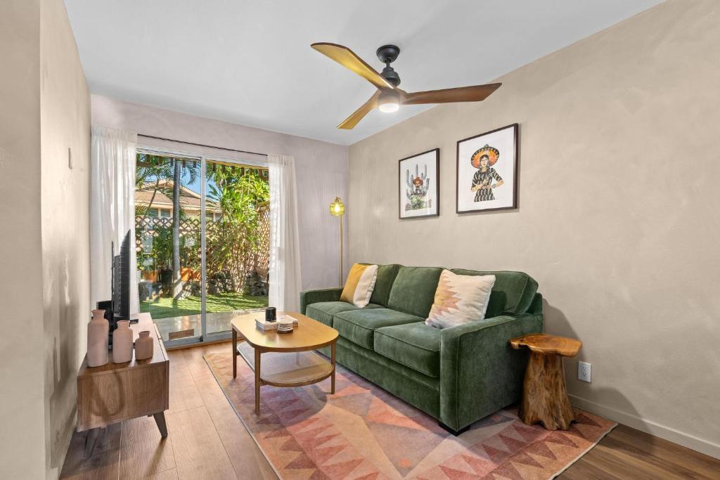 a living room with a green couch and a ceiling fan at Casa Aloha Designer Condo w Oceanfront Pool in Kailua-Kona