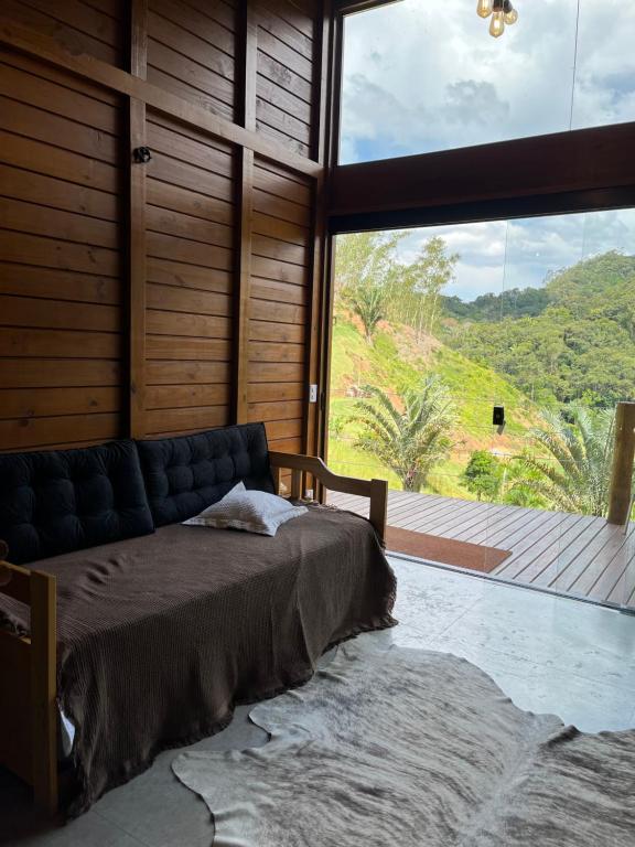a bedroom with a bed and a large window at Sítio Rancho Mineiro in Domingos Martins