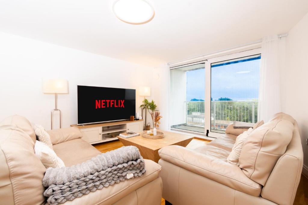 ein Wohnzimmer mit zwei Sofas und einem Fernseher in der Unterkunft Modern High-Floor 3BR with Terrace & Thames View in Kew Bridge