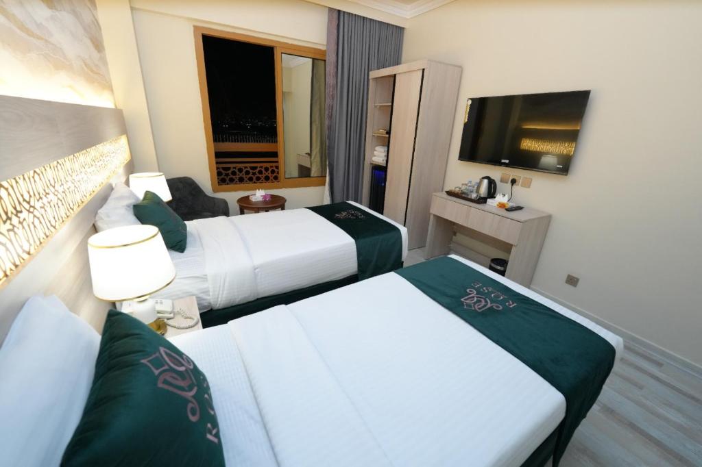 a hotel room with two beds and a television at Rose Holiday i3 روز هوليداي in Medina