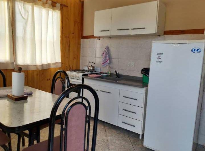 a kitchen with a table and a white refrigerator at Cabaña San Francisco in Cholila