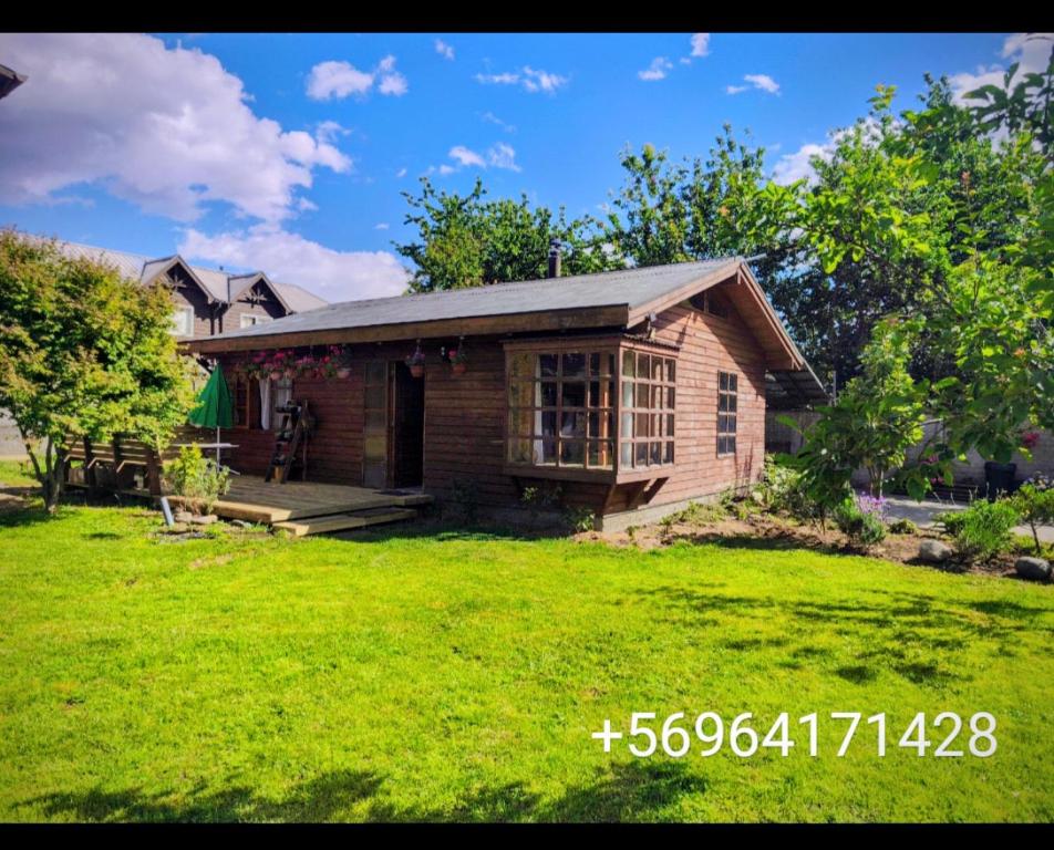 ein kleines Holzhaus mit einem Rasenhof in der Unterkunft Cabaña pasaje las rosas in Pucón