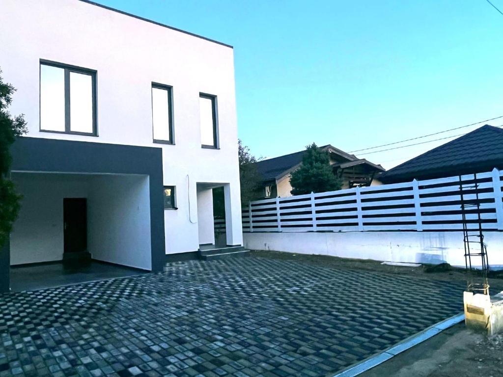 a white house with a fence and a brick driveway at Casa in Şimnicu de Jos