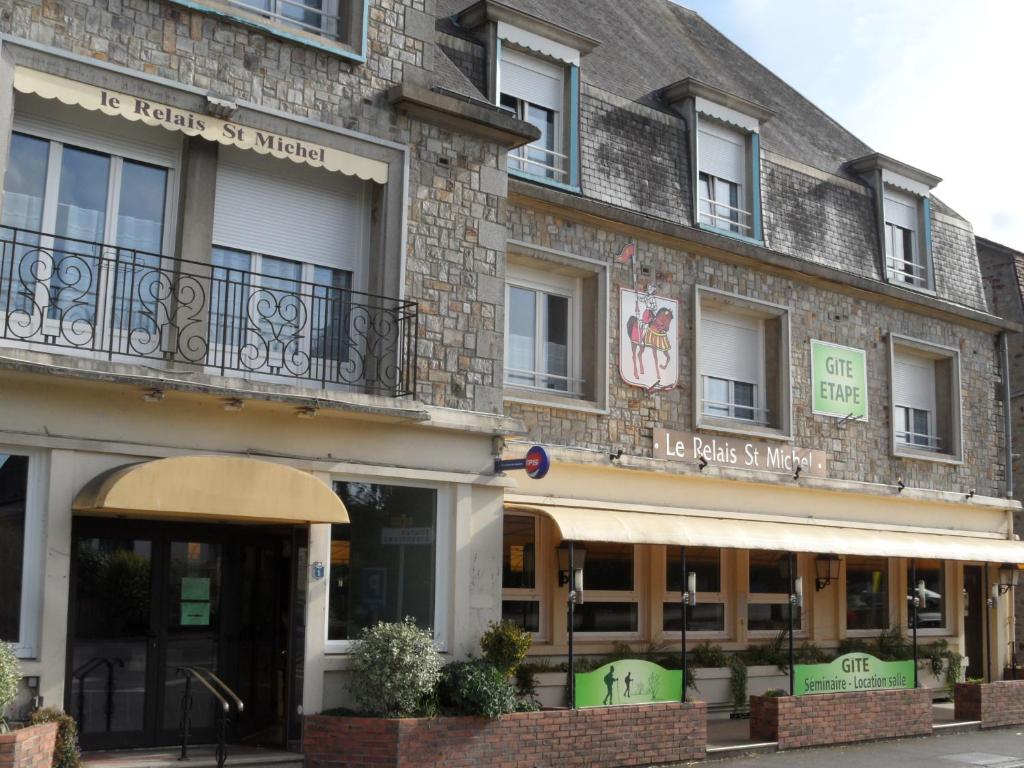 ドンフロンにあるGite Le Relais Saint Michelの窓と店舗のある大きなレンガ造りの建物