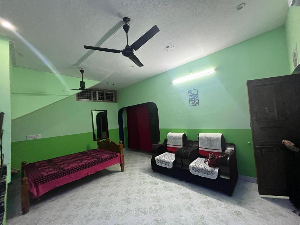 een kamer met twee bedden en een plafondventilator bij MB Guest House in Tiruvannamalai